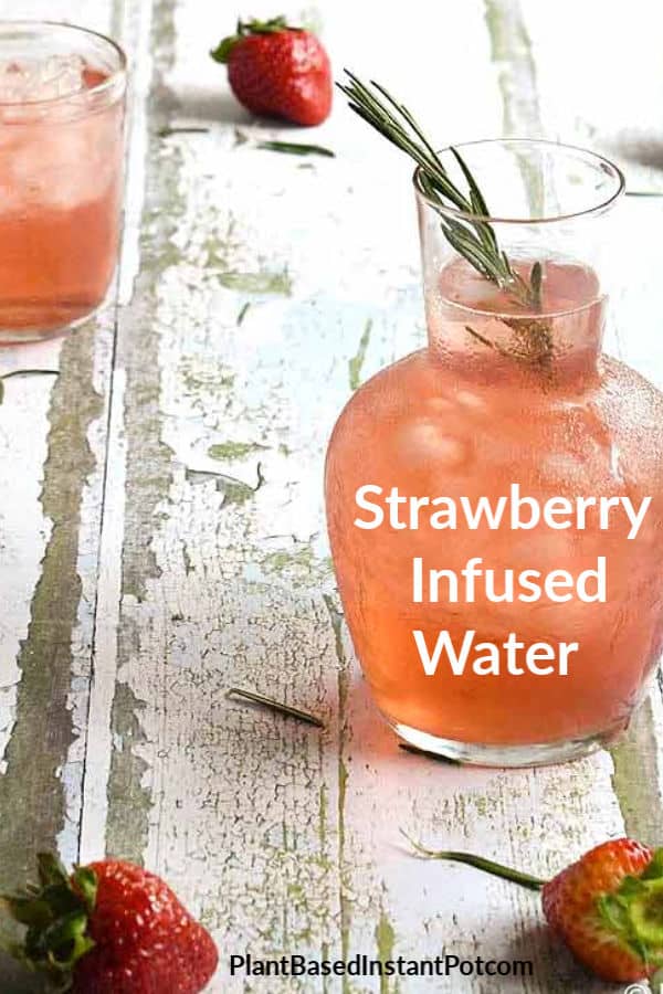 Strawberry Infused water with rosemary in a glass carafe and glass.