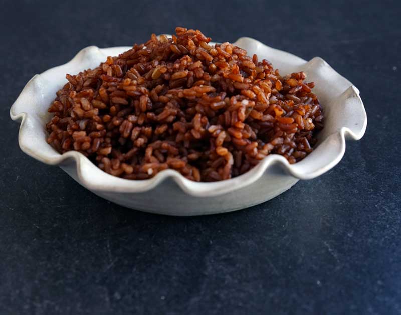 Cooked red rice in white ceramic pie plate