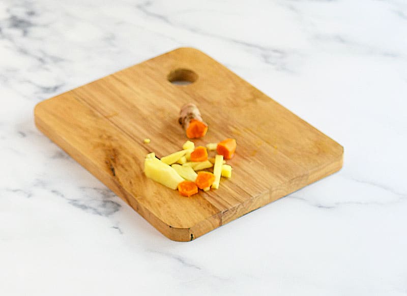 Fresh turmeric and fresh ginger on a wooden cutting board