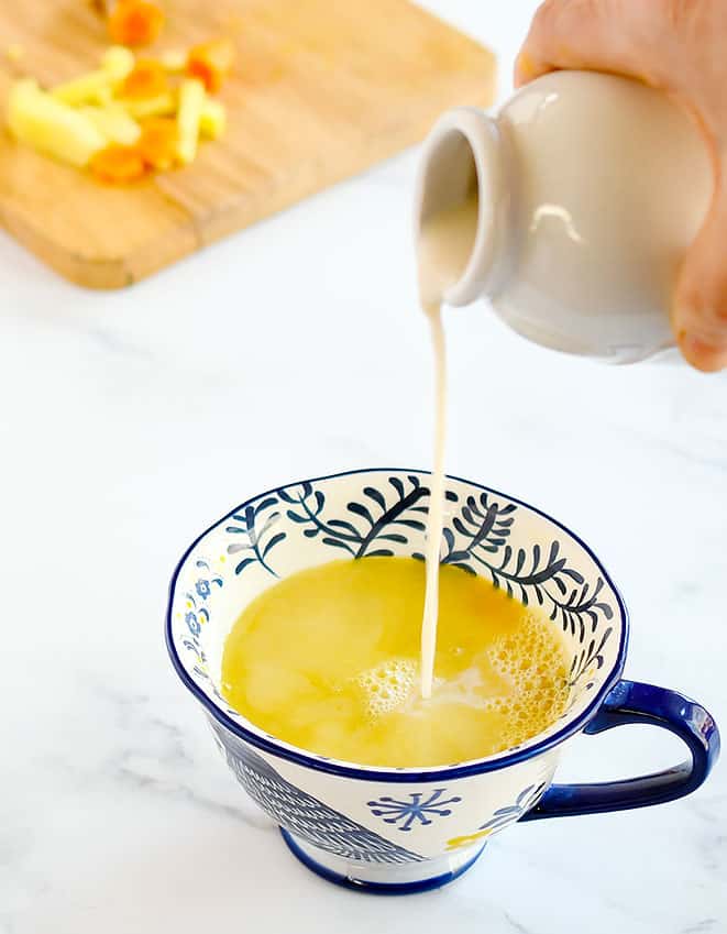 Vegan Nondairy creamer being poured into a cup with Turmeric Ginger Tea Concentrate