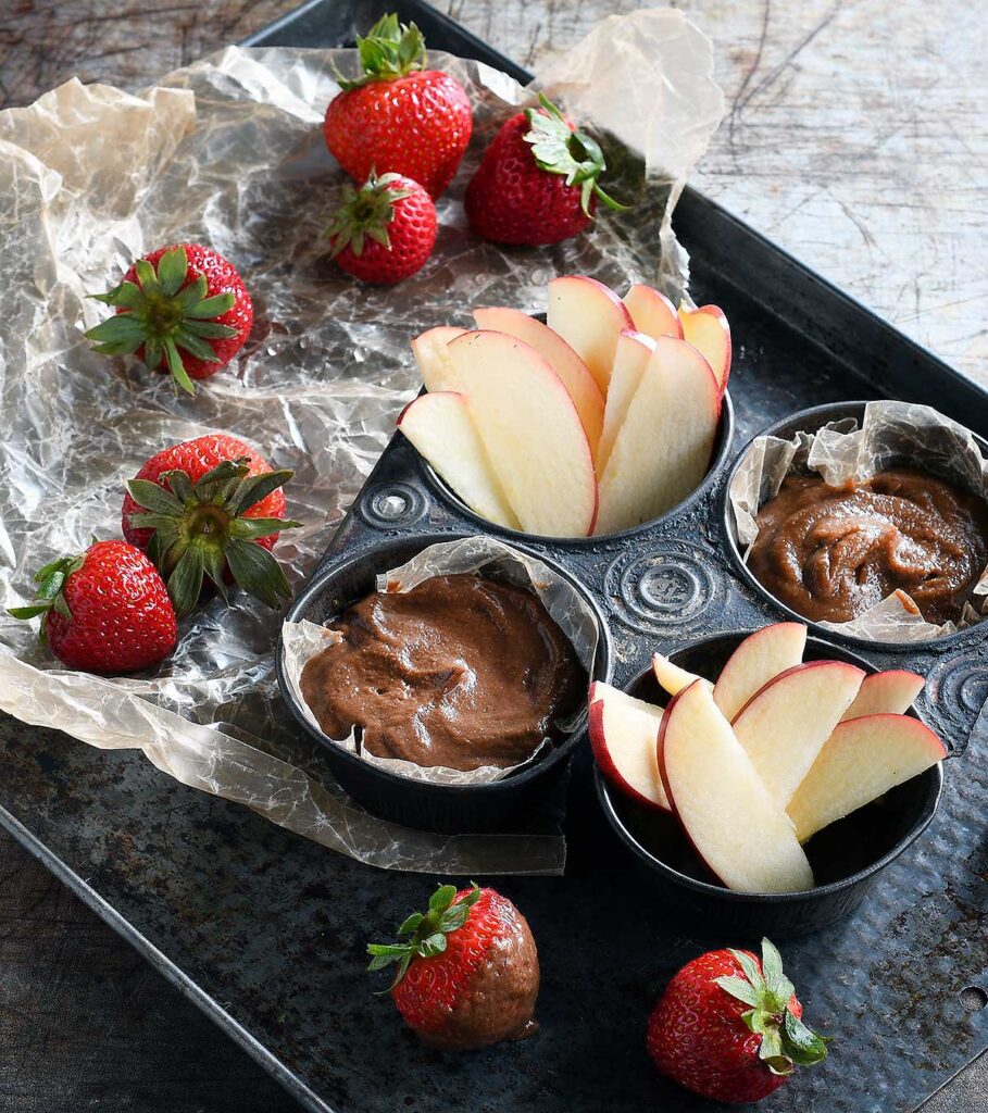 Dessert hummus on an antique cookie sheet with sliced apples and fresh strawberries.