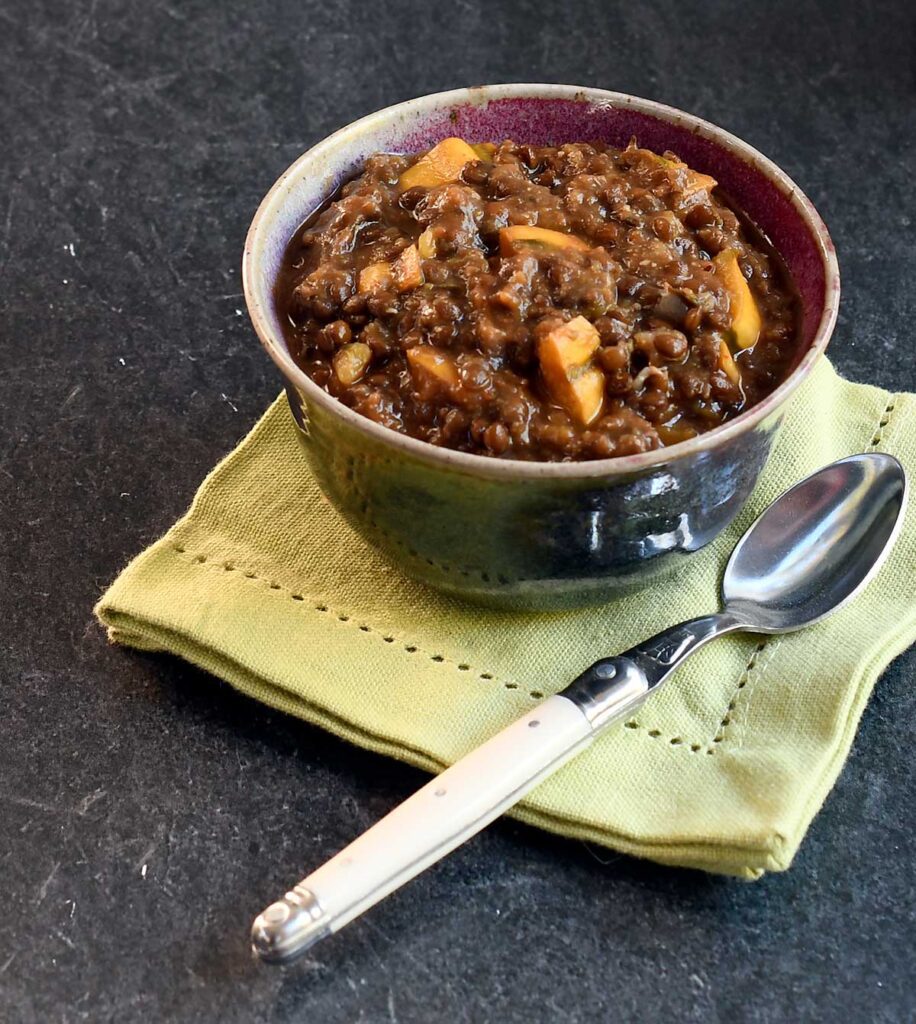 Vegan lentil soup with delicata squash in a pottery bowl.