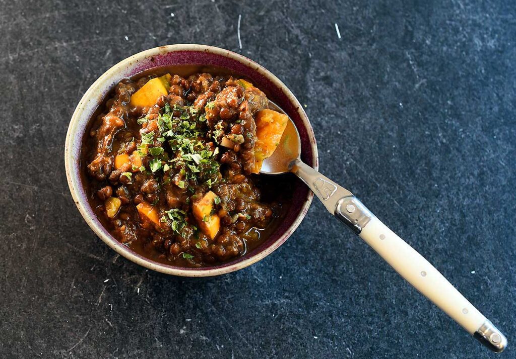 Instant Pot Lentil Soup with Winter Squash in a bowl with a white spoon.