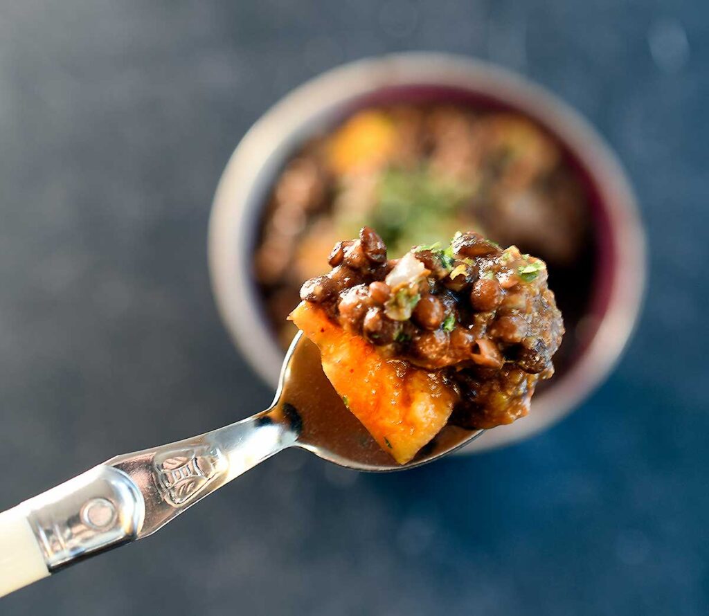 A bite of black lentils winter squash lentil soup on a spoon. 