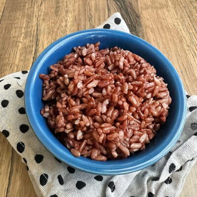 Cooked pink rice in a blue bowl.