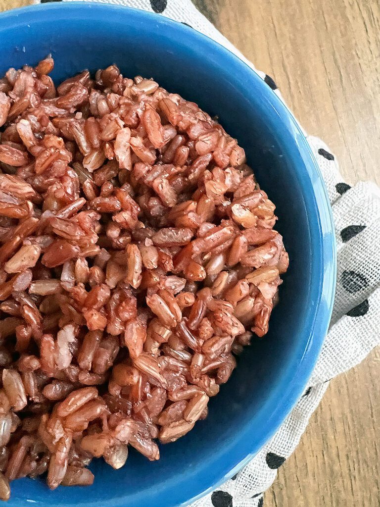 Cooked madagascar pink rice in a blue bowl.