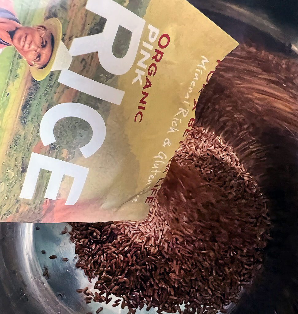 Pink rice being poured into an Instant Pot liner.